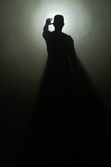 Silhoutette eines Mannes, der die Hand hebt im gleissenden Gegenlicht