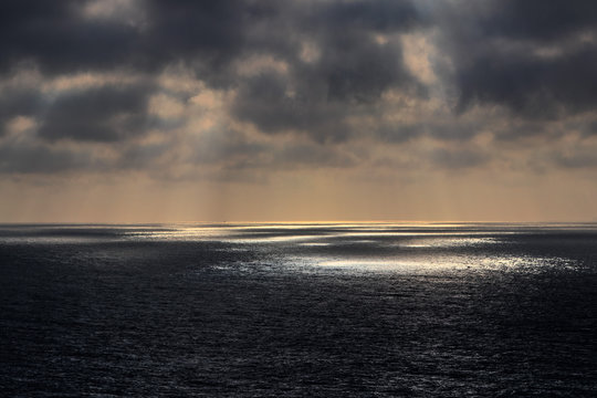 Dunkle Wolken lassen einzelne Lichtspots auf den Ozean strahlen