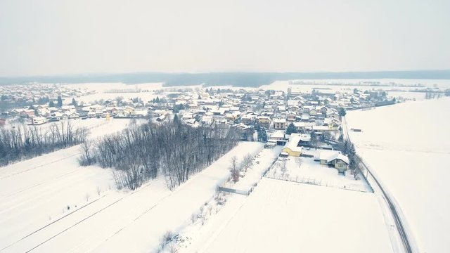 Winter city aerial shot 4K. Aerial drone shot wide view of a small town in winter surrounded by white fields.