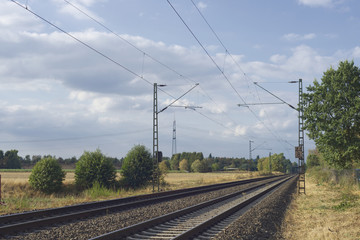 Fototapeta na wymiar Railway tracks in a rural scene along with electricity posts in outskirt of Düsseldorf, Germany
