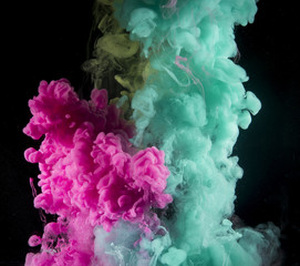Fototapeta premium Colorful rainbow paint drops from above mixing in water. Ink swirling underwater.