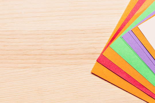 Color paper for origami lies on a fan of a light wooden table