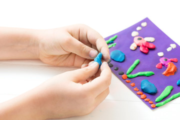 A child kneads plasticine and sculpts an aquarium with fish. Tutoring with children
