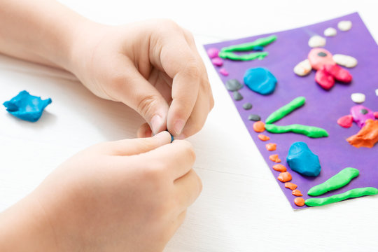 A child kneads plasticine and sculpts an aquarium with fish. Tutoring with children