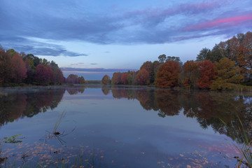 Obraz premium Pink clouds over autumn colored trees at the pond