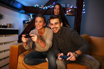 Group of best friends sitting at home on pleasant evening and playing games on console.They challenge each other to win .
