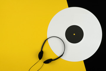 top view of a white long play vinyl record or LP with a black headphone on the yellow and black...