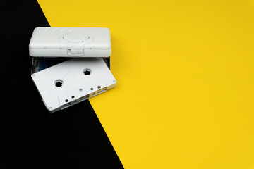 a white audio cassette tape with a white portable cassette player on the yellow and black background