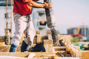 building construction worker pouring cement or concrete with pump tube