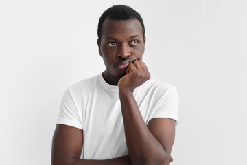 Indoor picture of young African American guy pictured isolated on gray background pressing fist to...
