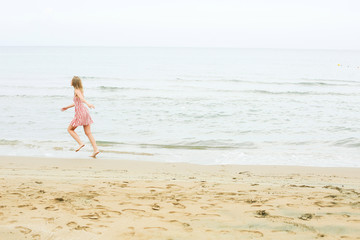 Fototapeta na wymiar woman is running along seashore, wearing short red dress