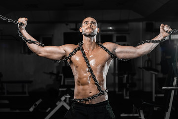Muscular man slave in chains in gym, the prisoner