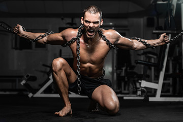 Fototapeta na wymiar Muscular man slave in chains in gym, the prisoner