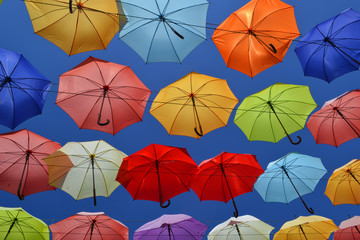 A lot of open multi-colored umbrellas against the blue sky.