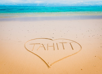 Tahiti beach with drawing heart and handwritten word in the sand.
