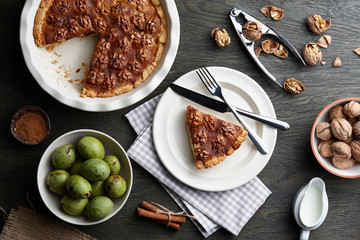 Traditional walnut pie with spices and nuts on dark wooden table, top view