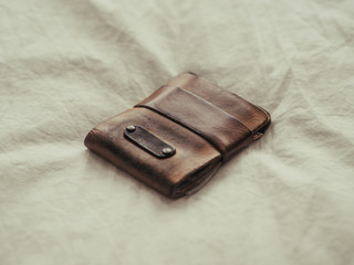 Used leather wallet left on bed.
