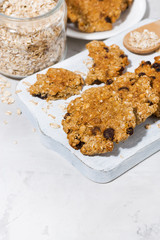 homemade oatmeal cookies with raisins on white wooden board, vertical