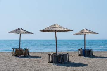 Panorama with sandy beach with wooden umbrellas and deck chairs