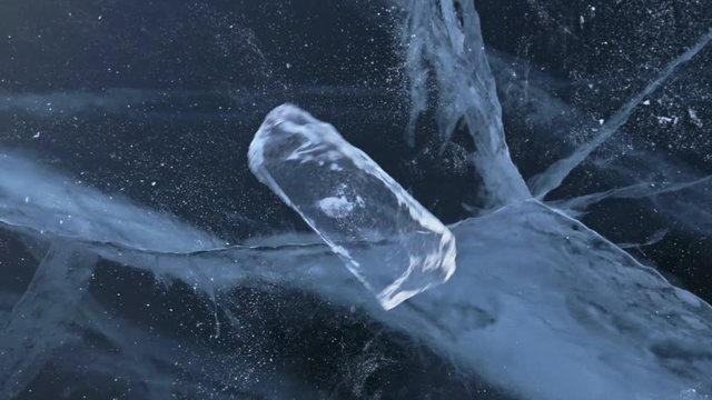 The ice floe rotates on the ice against the background of the amazing mountain landscape. Slow motion. The camera moves behind the ice. A piece of icy is very beautifully spinning on ice with magical
