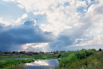 Naklejka premium rural landscape. The sun's rays make their way through the clouds and Shine on the house after a thunderstorm