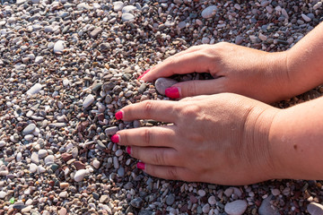 Women's hands play with pebbles on the beach