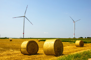 Wind turbines to create energy with hay field in front create a scenic view