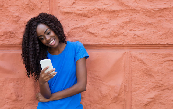 Beautiful African American Woman In A Blue Shirt Texting Message With Mobile Phone