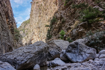 sunny day in the mountains; the mountain passage between the big mountains on both sides; a view from the bottom to the mountain walls, which forms interesting layers and structure