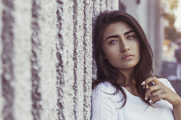 Fototapeta premium Fashion portrait of a beautiful young woman. Sexual brunette female outside looks into the camera. 