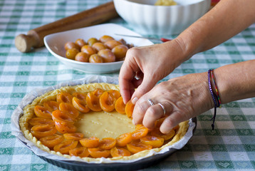 prune tart preparation decorated with fresh fruit cut in half