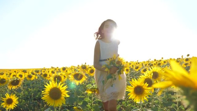Happy little girl running happy free across the field with sunflowers. slow motion video. smelling big sunflower on summer field. Delight of a pleasant smell lifestyle. Summer holiday. concept