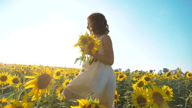 Happy little girl running happy free across the field with sunflowers lifestyle. slow motion video . smelling big sunflower on summer field. Delight of a pleasant smell. Summer holiday. concept