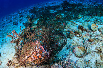 Fototapeta na wymiar A discarded ghost fishing net entangled on a tropical coral reef