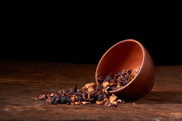 fruit tea in a clay bowl on a wooden table and black background. Selective focus