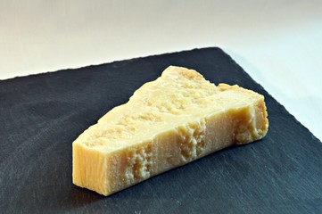 piece of italian grana cheese on ardesia plate