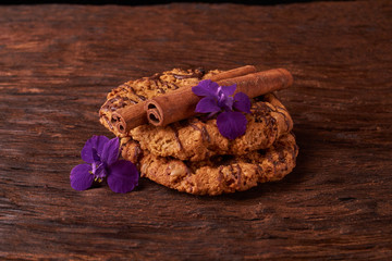 watered chocolate syrup cookies on wooden table. Cute composition with flowers and sticks of cinnamon. Selective focus