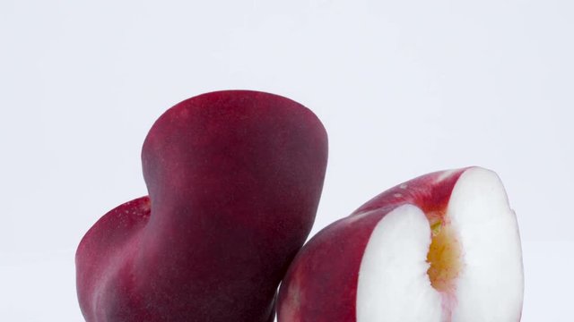 Macro shooting of two halves of a doughnut flat peach with the pit. Slowly rotating on the turntable isolated on the white background. Close-up