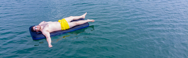 man on mattress in blue water. summer time concept