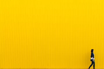 Frau, die in der Nähe der gelben Wand spazieren geht, Raumhintergrund kopieren © Frostroomhead