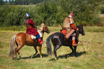 Summer. Reconstruction. Medieval armored knights on horse. Soldiers in historical costumes....
