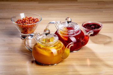 two teapots with sea buckthorn and raspberries