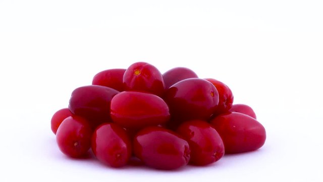 Closeup shooting of a pile of cornelian cherry dogwood fruits rotating on the turntable isolated on the white background. Side view. Macro.