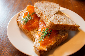 Simple yet tasty and delicious sandwich made with whole wheat bread, smoked salmon and cream cheese, garnish with fresh dill. A healthy choice snack or light lunch. Selective focus. Natural light.