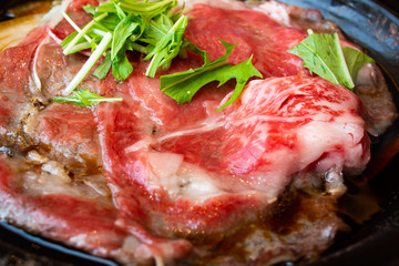 Tasty and delicious Japanese Sukiyaki nabe with best-quality cuts of thinly sliced sirloin or rib eye or tenderloin Kuroge Wagyu beef in a cast iron pan. Good Marble Score. Natural light. Close up.