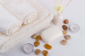 Spa and wellness setting soap white towels flowers stones candles aroma sticks white background