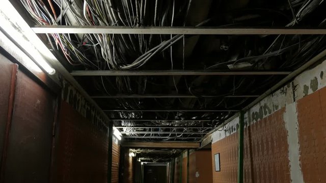 Basement floor of an building with many pipes and wires on ceiling without finishing.