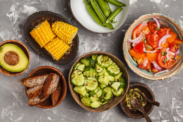 Clean eating concept. Cucumber salad, tomato salad, flax bread, avocado, corn. Top view, food background.