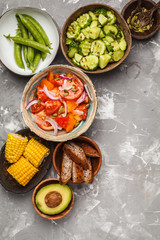 Clean eating concept. Cucumber salad, tomato salad, flax bread, avocado, corn. Top view, food background.