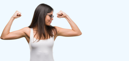 Fototapeta na wymiar Young beautiful hispanic wearing sunglasses showing arms muscles smiling proud. Fitness concept.